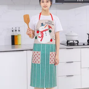 Festive Christmas linen apron with snowman print and green stripes worn by a woman