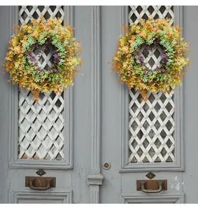 Detailed view of two vibrant spring daisy wreaths hanging on a vintage grey wooden door