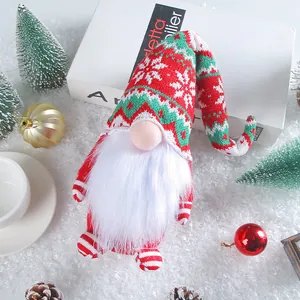 Handcrafted knitted Christmas gnome doll with snowflake hat on artificial snow decor.