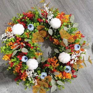 Herbstkranz mit Eukalyptus, weißen Kürbissen und blauen Blumen auf grauem Boden