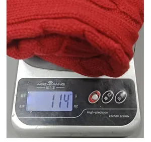 Red knitted Christmas stocking weight measurement on digital scale showing 114g