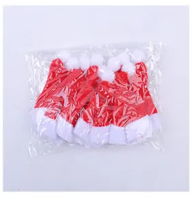 Bulk pack of mini red non-woven Santa hats for Christmas cutlery and bottle decor.