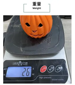 Detailed view showing the 26g weight of a glowing Halloween pumpkin bucket on a scale