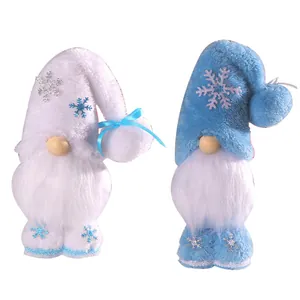 Due gnomi di Natale in piedi con motivi a fiocco di neve in peluche blu e bianco