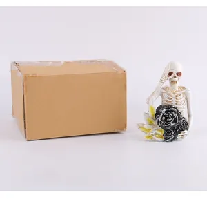 Figurine de squelette d'Halloween avec roses noires à côté de sa boîte d'emballage