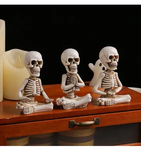 Trois figurines de squelette Halloween dans différentes poses de yoga sur un meuble en bois