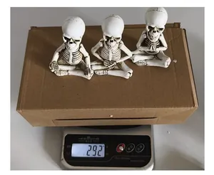 Mesure du poids de trois figurines de squelettes méditant en résine avec emballage