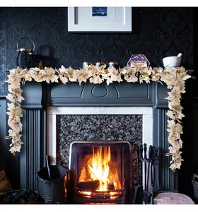 Artificial maple leaf and pumpkin garland draped over a fireplace mantel for fall decor.