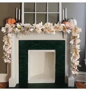 Realistic artificial maple leaf and pumpkin garland draped over an elegant white fireplace.