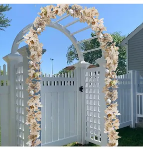 Close-up detail of artificial cream maple leaf and pumpkin garland on a garden arch