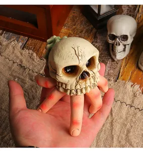 Detailed view of a spooky resin skull with ghost fingers held in a hand for Halloween.