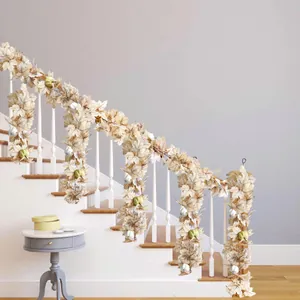 Artificial maple leaf and pumpkin garland draped on a staircase for autumn decor