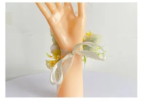Nahaufnahme einer gelb-weißen Brautjungfern-Handgelenksblume mit Schleifenband.