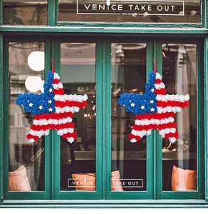 Patriotic star-shaped wreaths with red white and blue flowers displayed on a glass door