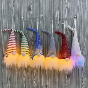 Set of 6 lighted Christmas gnome ornaments with sequined hats hanging on wood wall.
