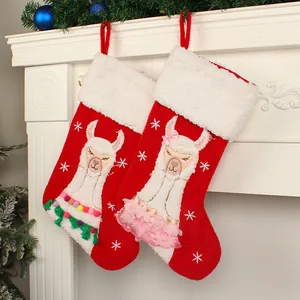 Pair of cute red Christmas stockings with alpaca appliques hanging on white fireplace