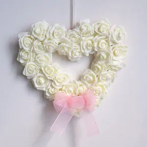 Heart-shaped white rose wreath with pink ribbon for Valentine's Day and wedding decor.