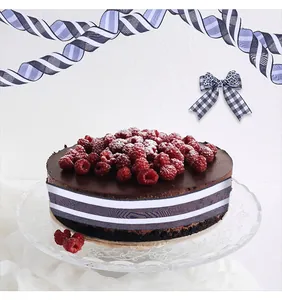 Close-up of black and white striped ribbon decorating a chocolate cake with raspberries