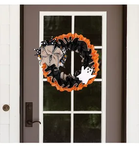 Close-up of Halloween ghost wreath with orange black ruffles and burlap bow on door