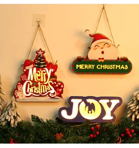 Collection of glowing Christmas wooden ornaments hanging on a wall with festive pine decor