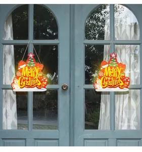 Pair of glowing Merry Christmas wooden signs hanging on a blue glass patio door.