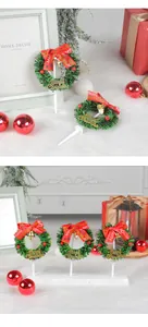 Miniature Christmas wreath cake toppers with red bows and bells in festive scene