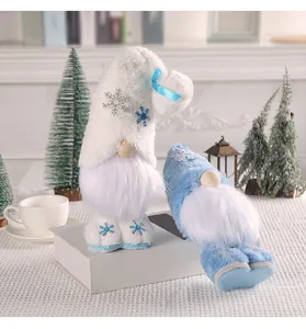 Set aus blauen und weißen Plüsch-Weihnachtswichteln mit Schneeflockenstickerei auf Tisch