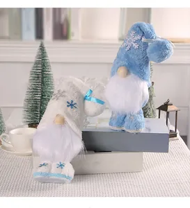 Nahaufnahme von weißen und blauen Weihnachtswichteln mit Schneeflocken auf festlichem Grund.
