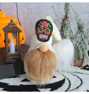 Détail d'un gnome d'Halloween avec un écusson brodé de tête de mort et de rose.