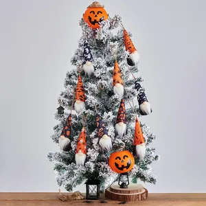 Detailed view of Halloween gnome ornaments hanging on a snowy white festive tree.