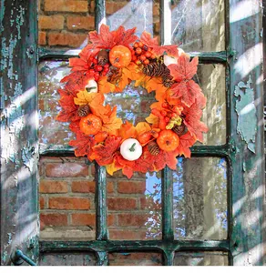 Mooie herfstkrans met esdoornbladeren en pompoenen hangend aan een rustiek vintage raam