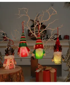 Close-up of glowing Christmas gnome ornaments with reindeer antlers on a white branch
