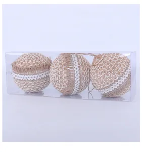 Close-up of three jute decorative Christmas balls with lace details in a clear box