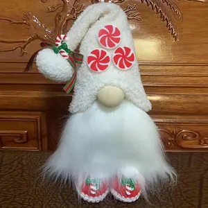 Close-up of a white plush Christmas gnome with peppermint candies and a candy cane bow.