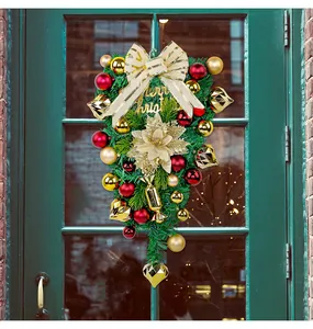 Detailed view of a Christmas teardrop wreath with red and gold ornaments on a green door.