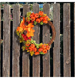 Detail of autumn harvest wreath with pumpkins and berries on a rustic wooden fence