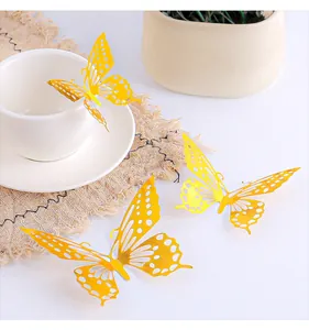 Dettaglio macro di tre adesivi murali a farfalla 3D gialli su una tazza e un piattino bianchi.