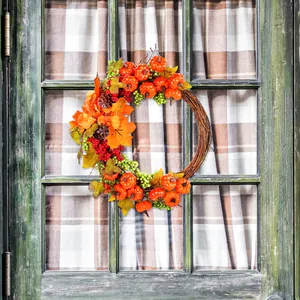 Autumn pumpkin wreath with maple leaves and berries on rustic door