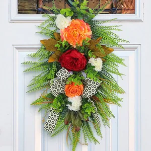 Detailed view of fall artificial peony floral door swag with green ferns and patterned ribbon