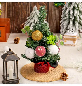 Close-up detail of a decorative mini Christmas tree featuring red and gold baubles on a straw mat