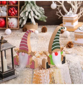 Close-up of pink and green wooden Christmas gnomes with white beards in snowy scene