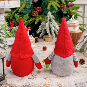 Two festive Christmas gnome plush dolls with tall red hats on a snowy winter background