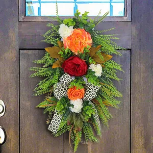 Autumn artificial floral door swag with orange peonies and fern leaves for harvest decor.