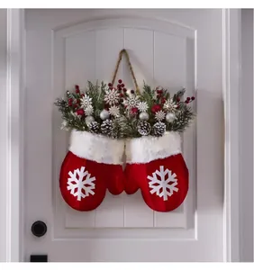 Détail de décoration de porte moufles de Noël rouges avec branches de pin et baies