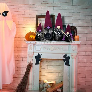 Gnomes d'Halloween sans visage avec chapeaux violets et écharpes rayées sur une cheminée