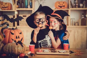 Enfants en costumes d'Halloween mangeant des sucettes citrouilles dans un décor festif