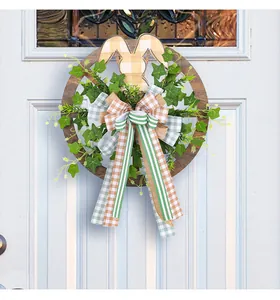 Détail de la couronne de Pâques en bois avec oreilles de lapin et ruban sur porte blanche.