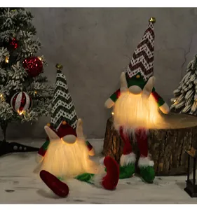 Two glowing faceless Christmas gnomes sitting on a wooden stump for holiday decor