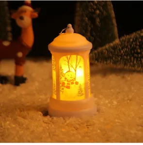 Warm glowing handheld Christmas lantern with snowman detail in festive snowy setting.