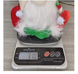 Close-up view of a luminous faceless Christmas doll being weighed, showing its 110g weight